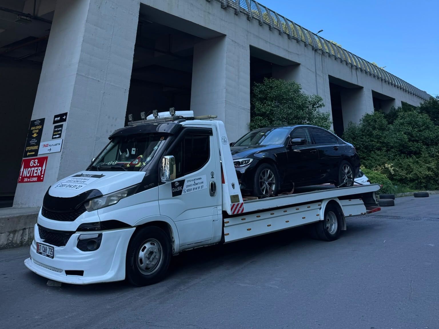 Viyadük altında siyah sedan taşıyan çekici